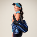 Woman holding a blue and black bag against a plain background